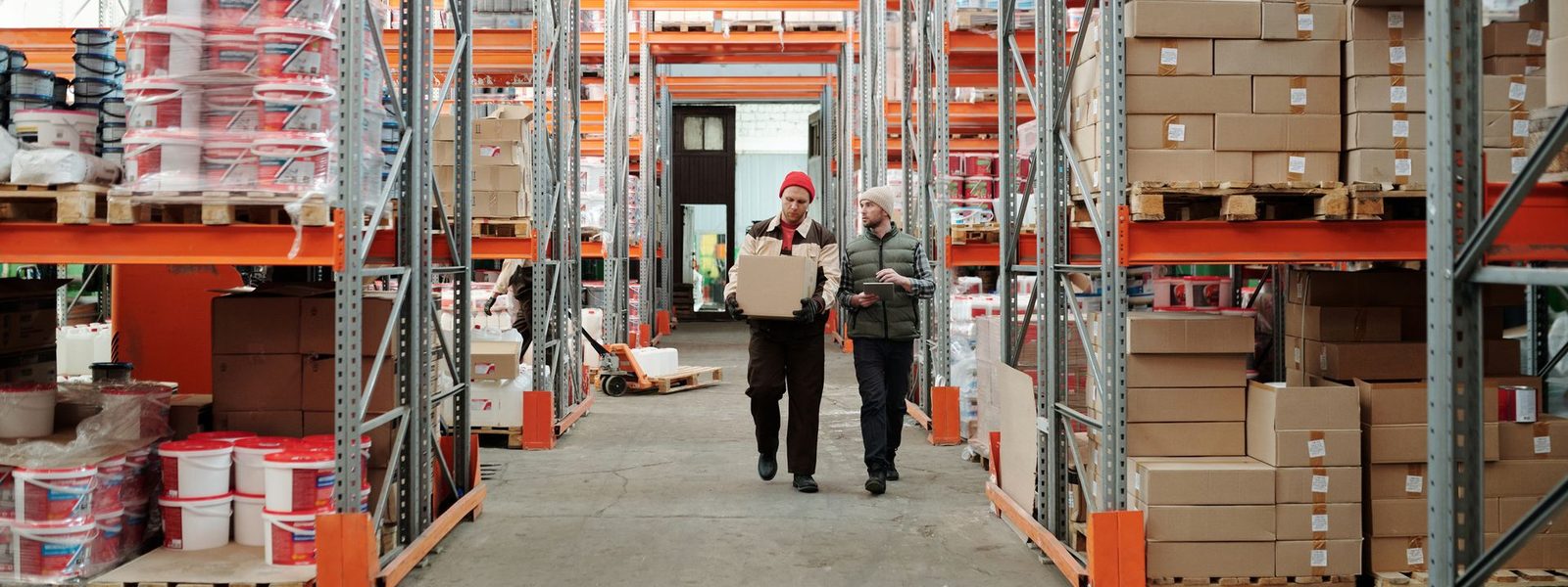 Two workers carrying stock down a warehouse aisle