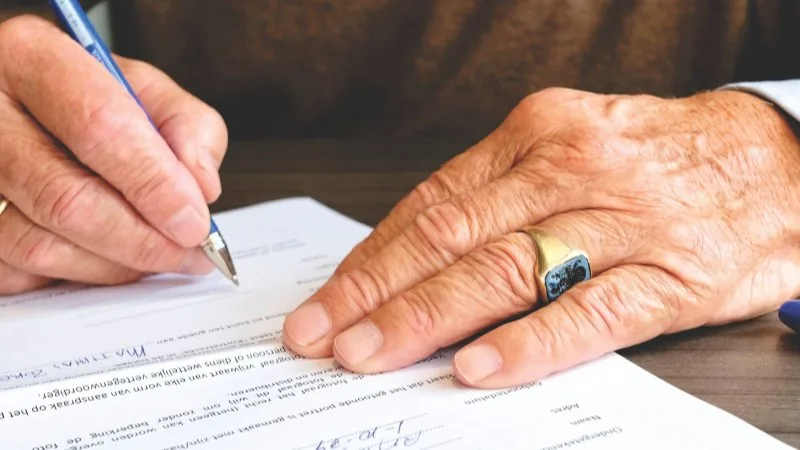 An older person signing a document