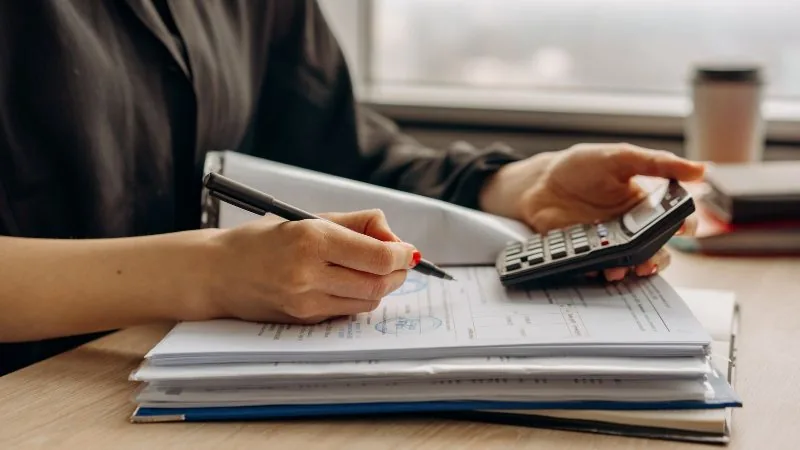 A person working through bills and statements with a calculator