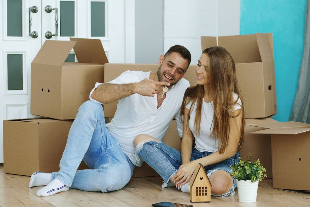 A couple sitting among moving boxes in their new home